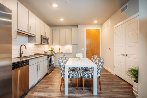A modern kitchen with a dining table set for two.