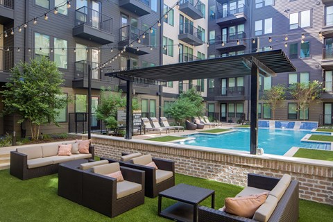 A patio with a pool and a black umbrella.