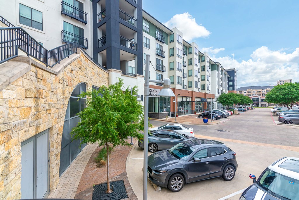 A parking lot with cars and a building with a stone wall.