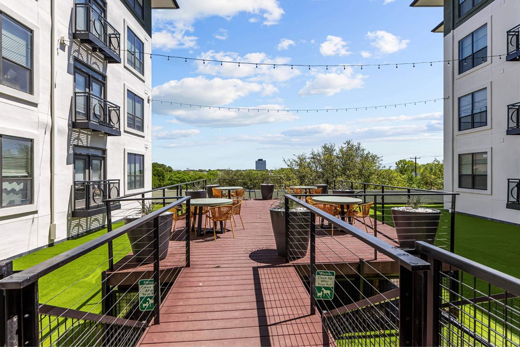A patio with tables and chairs is surrounded by white buildings.