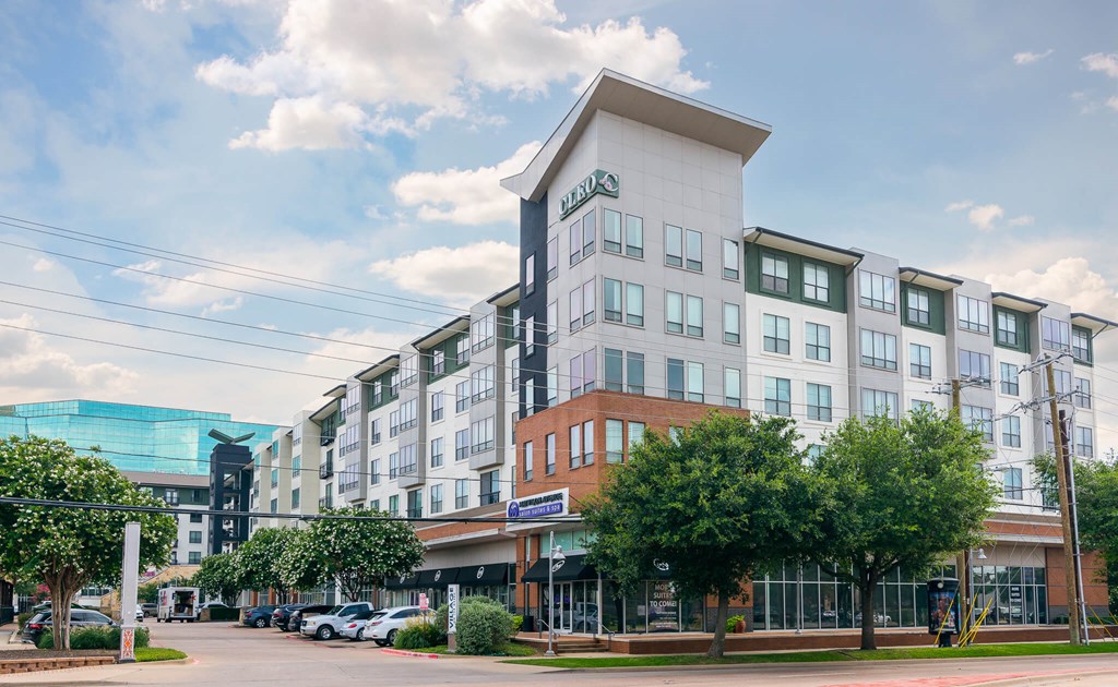 A large white building with a green sign on the top left corner.