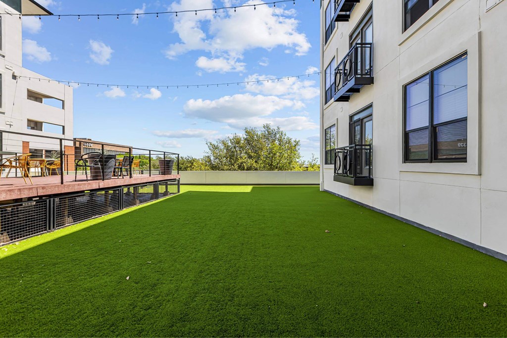 A rooftop with a green lawn and a white building.