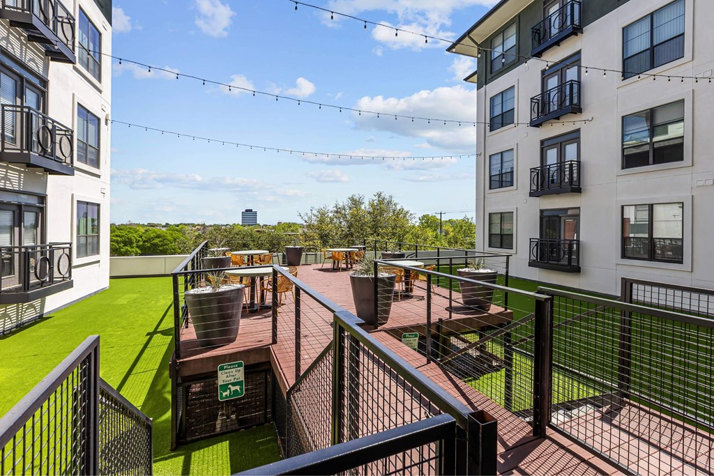 A patio area with a table and chairs is surrounded by a metal fence.