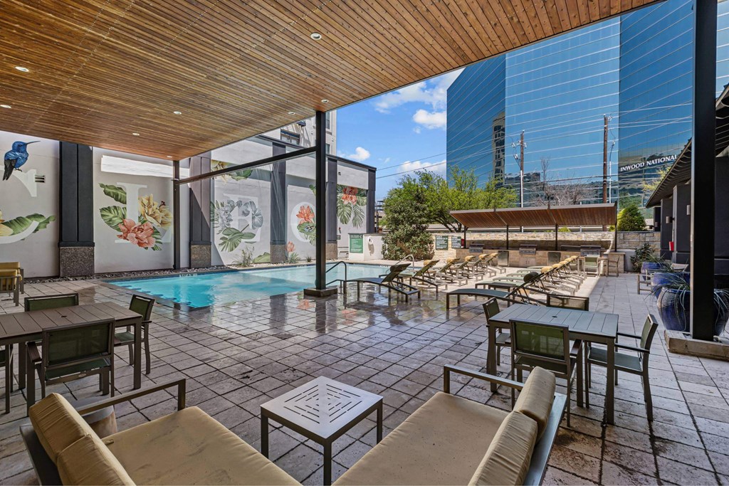 A modern outdoor seating area with a pool and a view of the city.