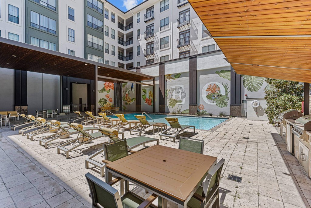 A patio with a table and chairs overlooking a pool.