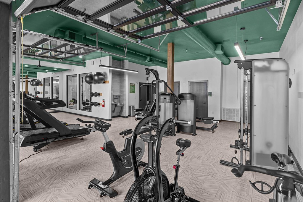 A gym with a variety of equipment including treadmills, weights, and exercise bikes.