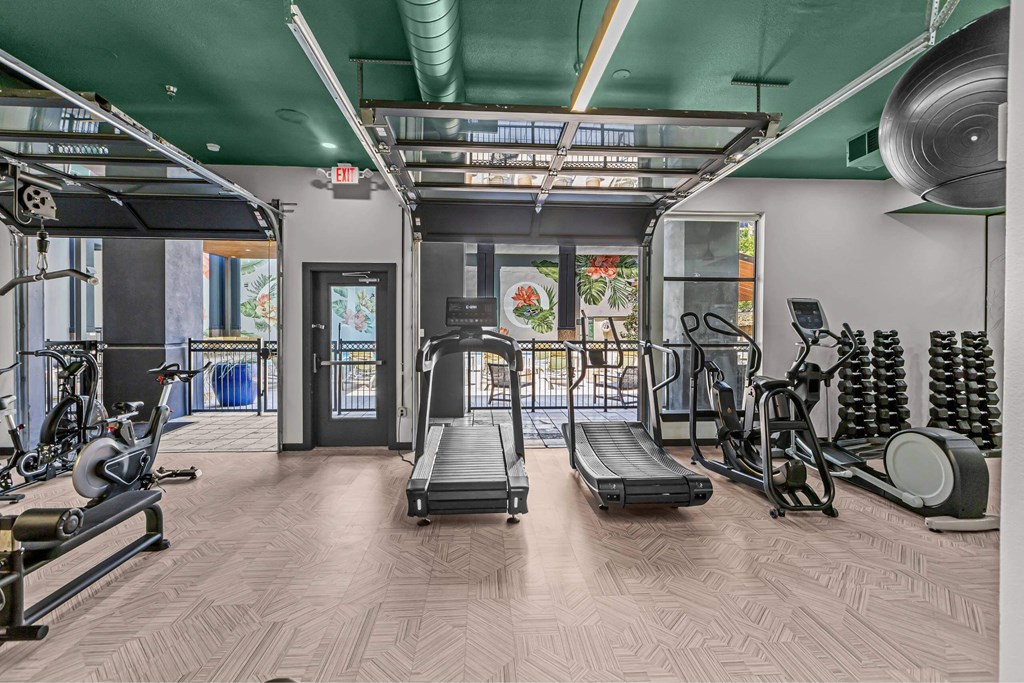 A gym with a variety of equipment including treadmills, weights, and exercise machines.