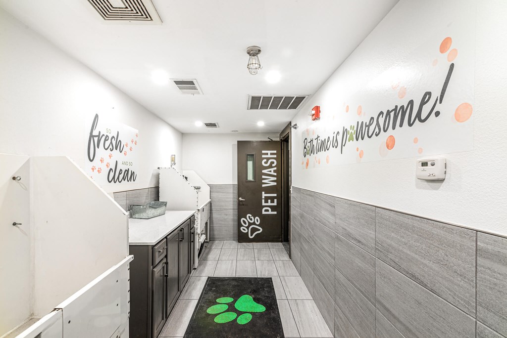 A hallway with a green paw print rug and a sign that says "Happy Pet Week!"