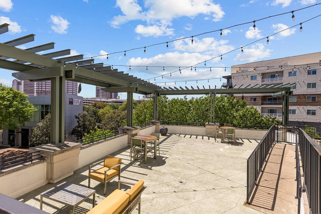 A rooftop patio with tables and chairs under a pergola.