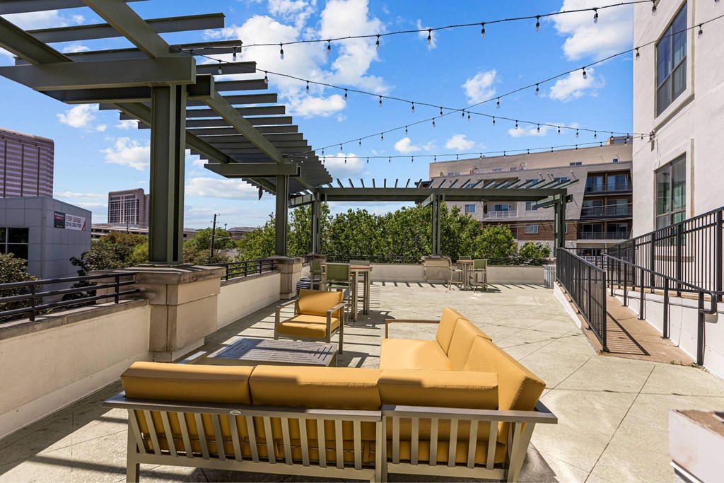 A patio with yellow couches and a black railing.