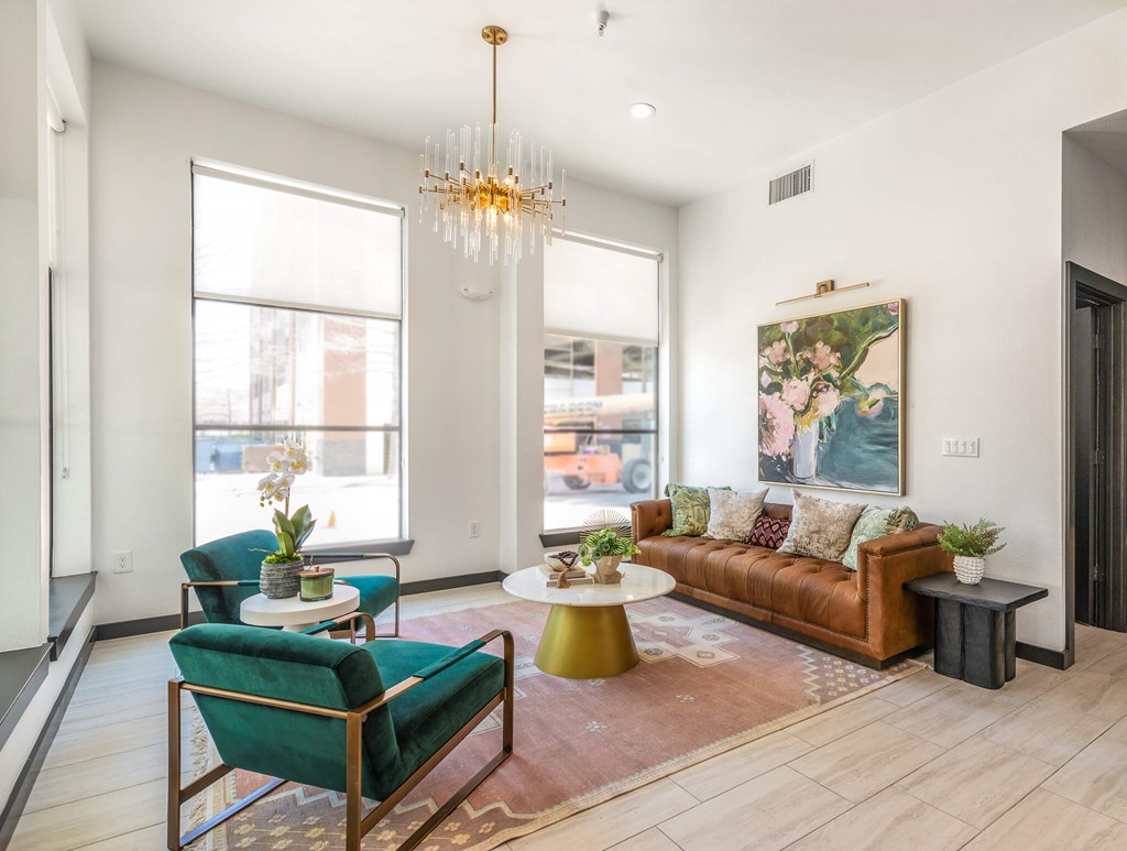 A living room with a green chair, a brown couch, and a chandelier.