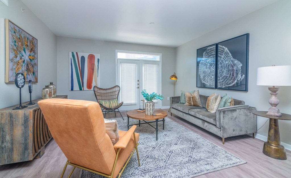 A living room with a chair, a sofa, a table, and a painting on the wall.