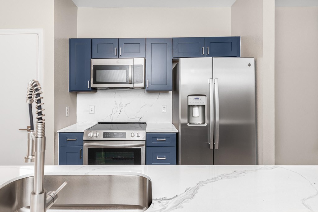 A kitchen with a stainless steel refrigerator, microwave, oven, and sink.