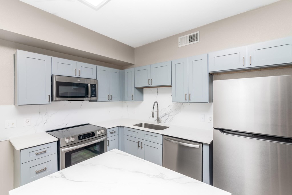 A kitchen with a stove, oven, refrigerator, and microwave.
