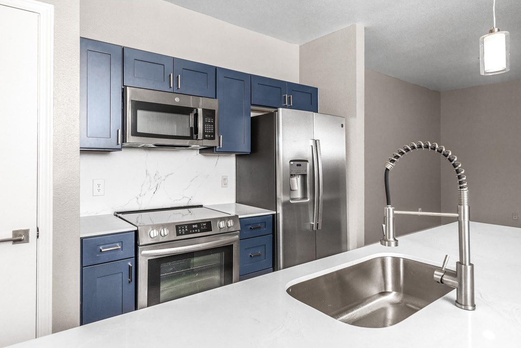 A kitchen with blue cabinets and stainless steel appliances.
