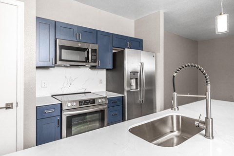 A kitchen with blue cabinets and stainless steel appliances.