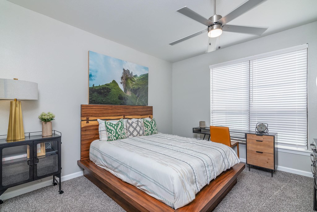 A bedroom with a bed, nightstand, and a painting on the wall.
