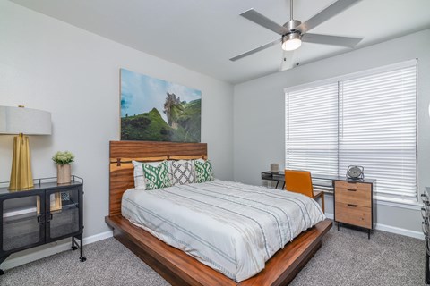 A bedroom with a bed, nightstand, and a painting on the wall.