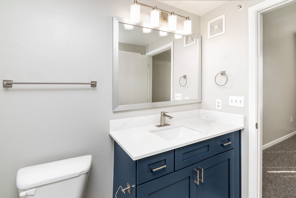 A bathroom with a white counter top and blue drawers.