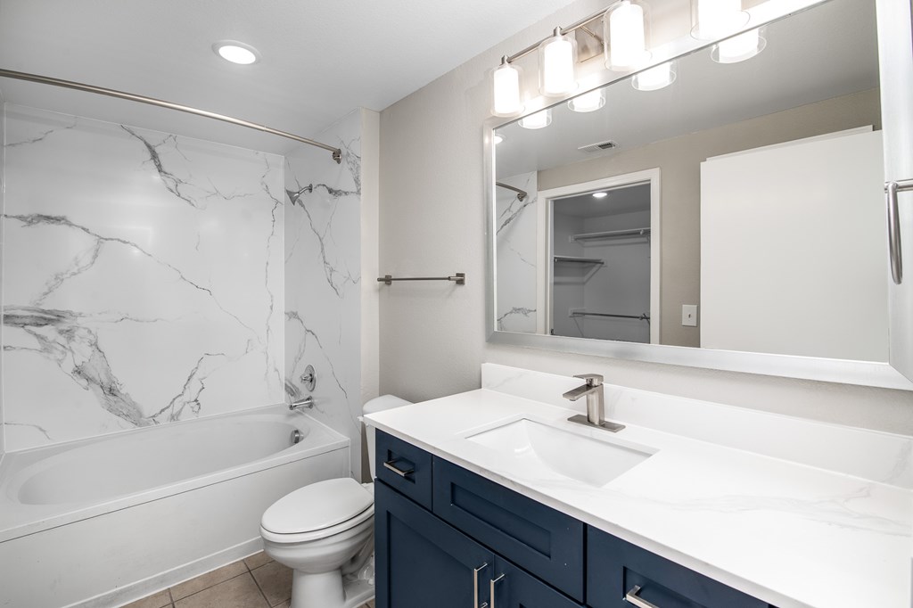 A white bathroom with a marble wall and a white toilet.