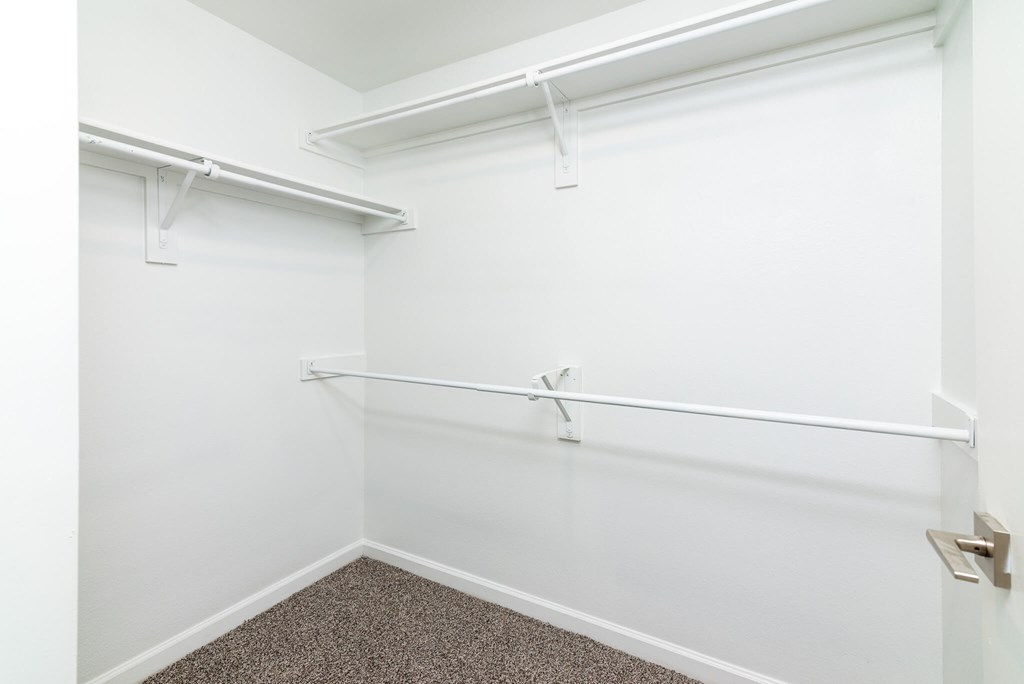 A white wall with a white door and a white shelf.