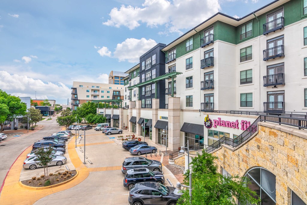 A parking lot with cars and a building with a Planet Fitness sign.