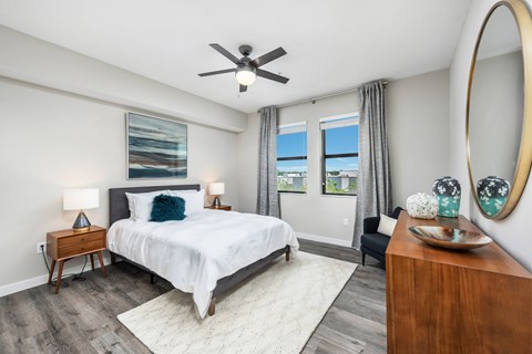 A bedroom with a large bed, a ceiling fan, and a view of the outdoors through the window.