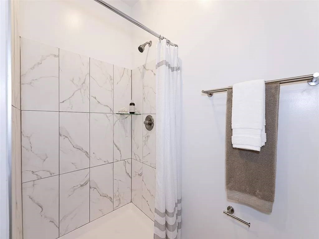 A white bathroom with a marble tile shower.