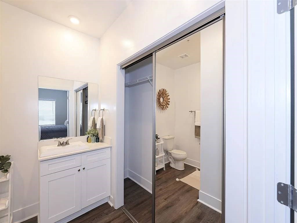 A bathroom with a white cabinet and a mirror above it.