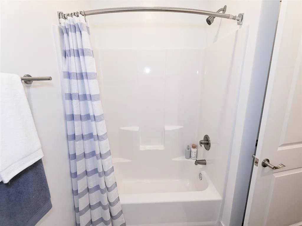 A white bathtub with a blue and white striped shower curtain.
