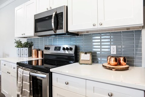 A modern kitchen with a black stove and white cabinets.