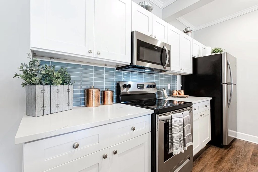 A kitchen with white cabinets and a black refrigerator.