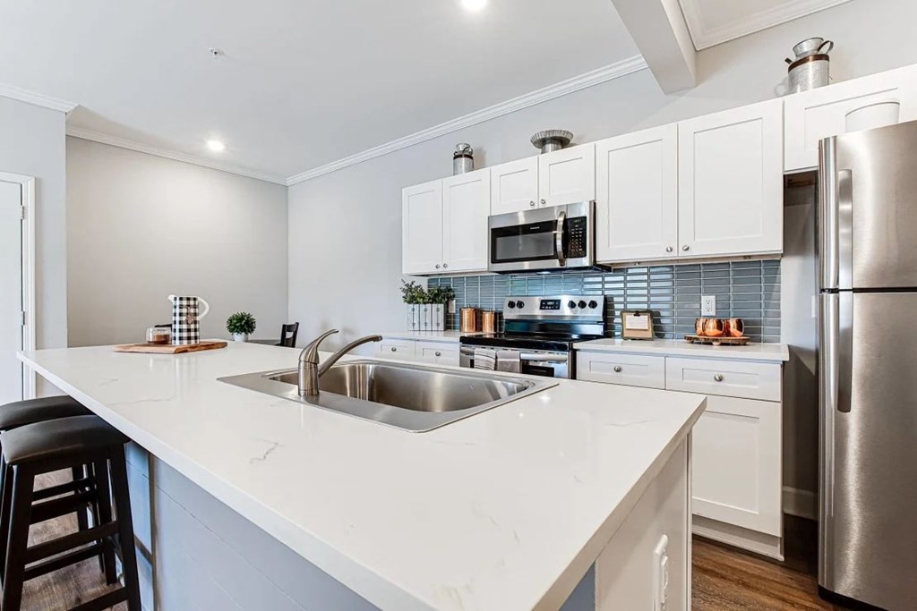 A modern kitchen with white cabinets and stainless steel appliances.