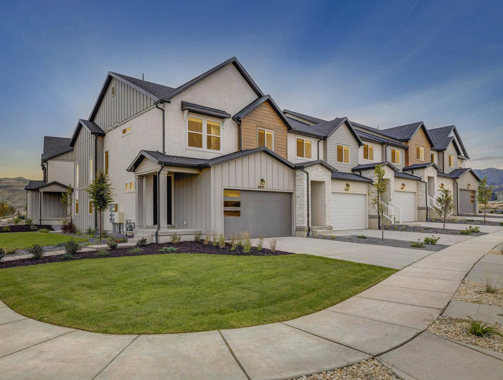 A row of modern houses with a well-maintained lawn in front.
