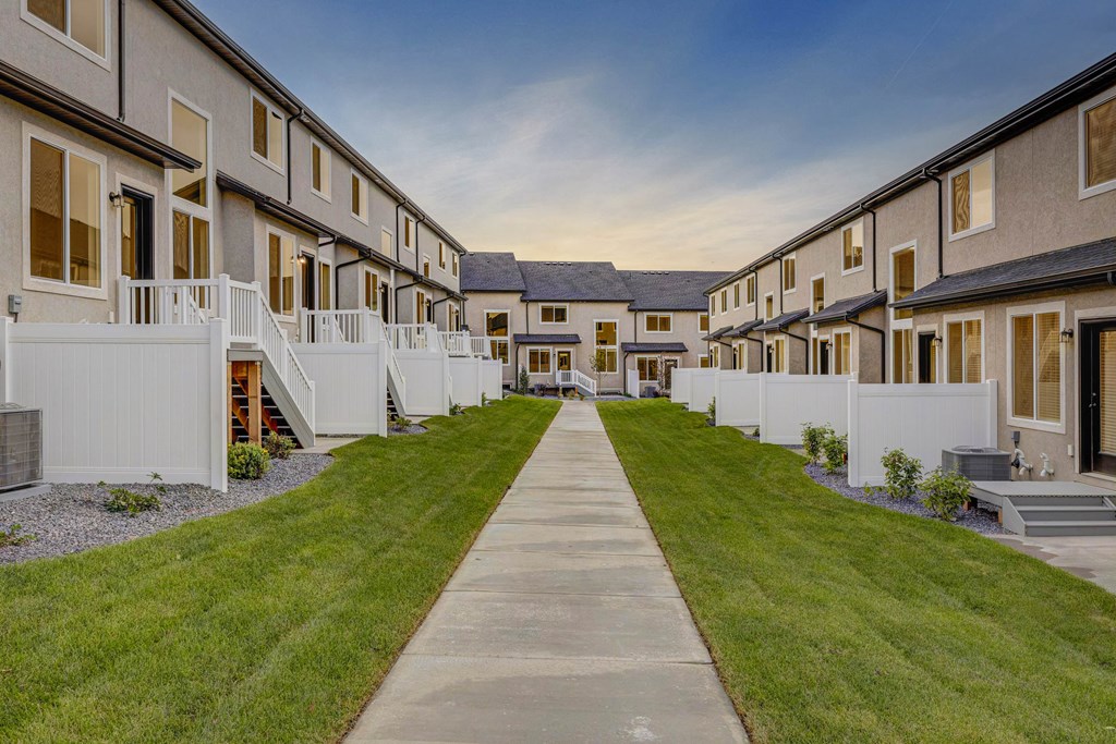 A long concrete walkway leads between a row of houses.