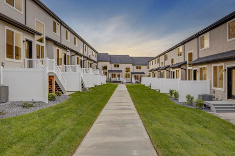 A long concrete walkway leads between a row of houses.