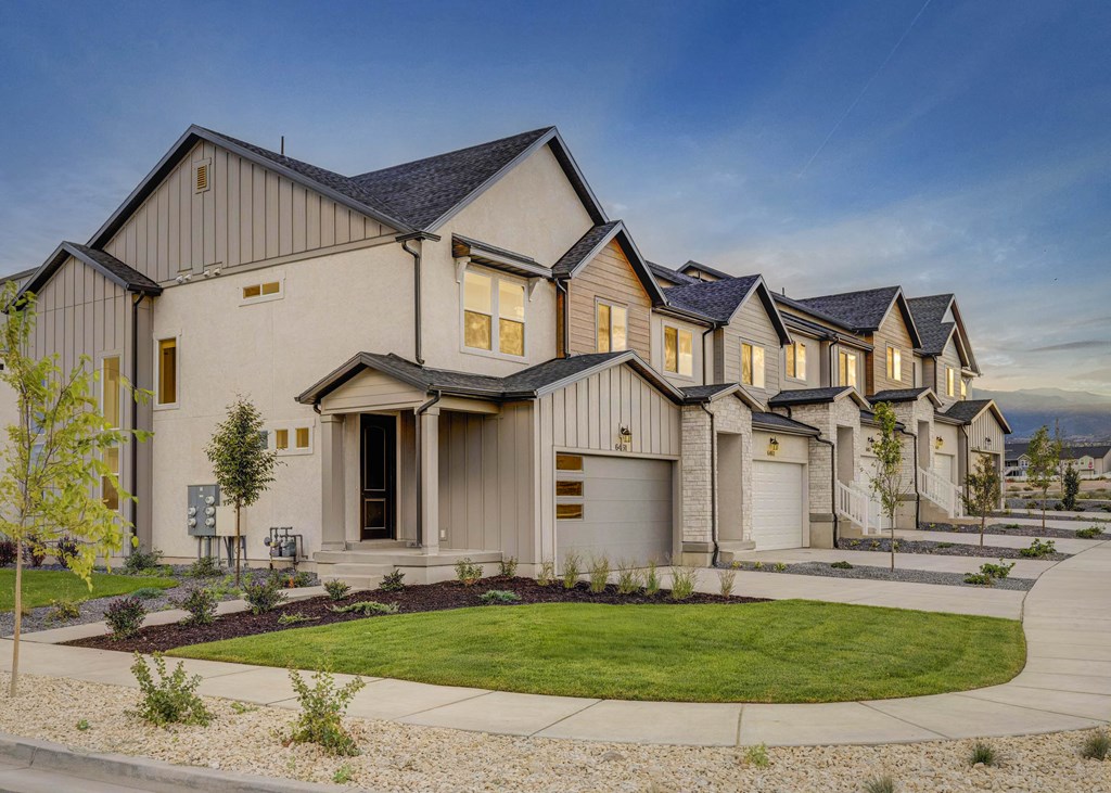 A row of houses with a front yard and a sidewalk.