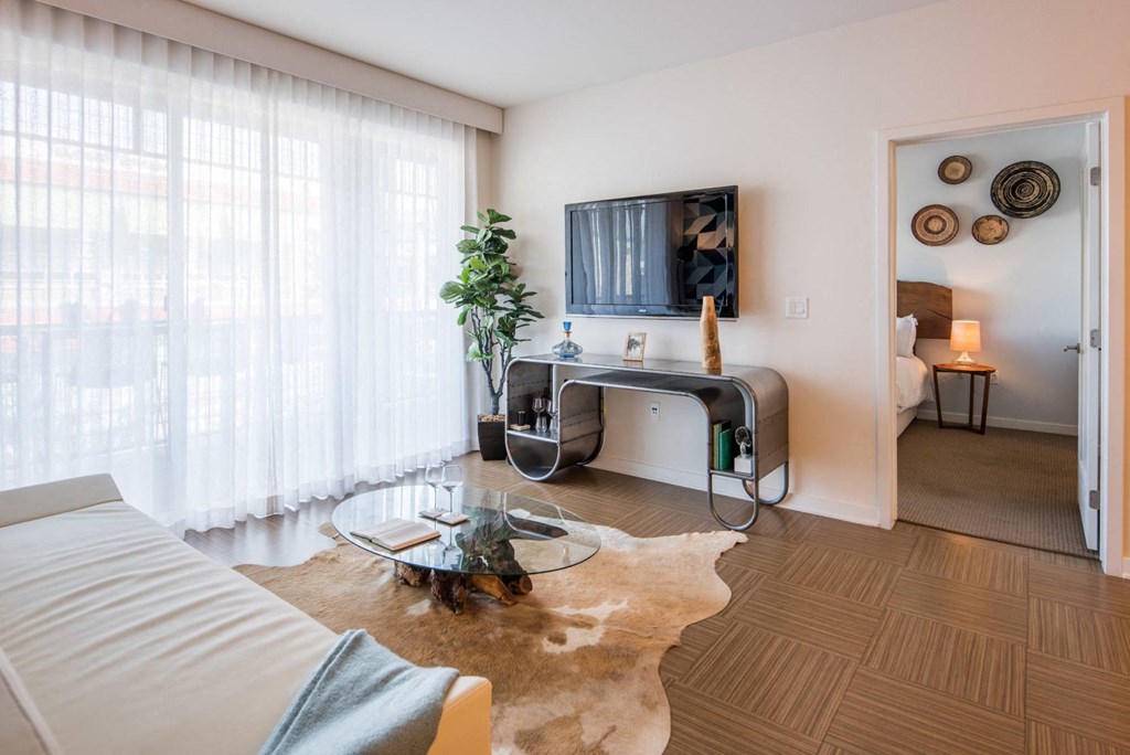 A living room with a white couch and a glass coffee table.