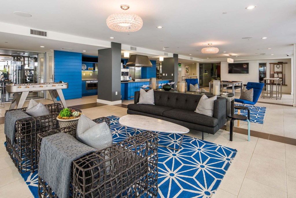 A modern living room with a black sofa and a blue patterned rug.