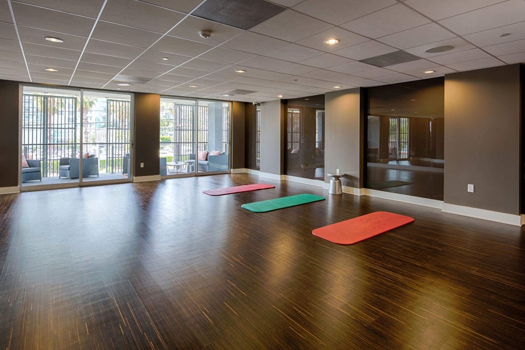 A yoga studio with a wooden floor and a large window.