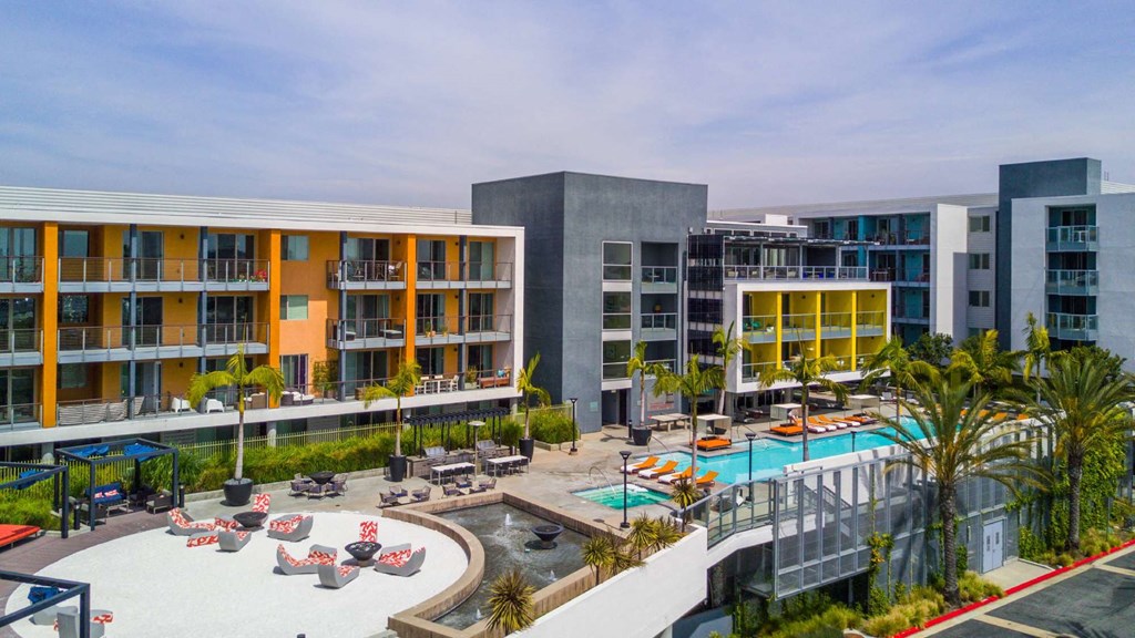 A modern building complex with a pool and lounge chairs.