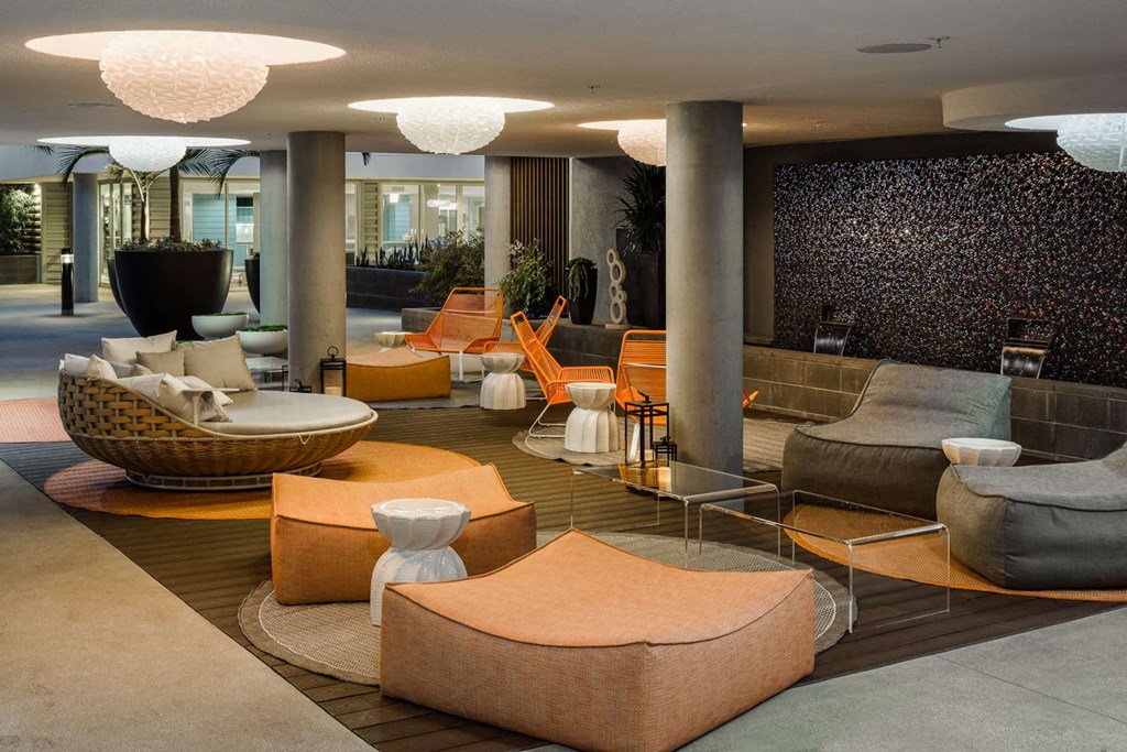 A modern living room with a variety of seating options and a patterned wallpaper.