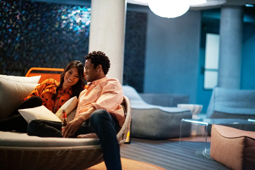 A man and woman are sitting on a couch, looking at a laptop together.