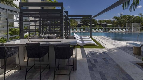 A modern outdoor dining area with a table and chairs overlooking a pool.