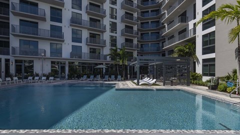 A large swimming pool in front of a multi-story residential building.