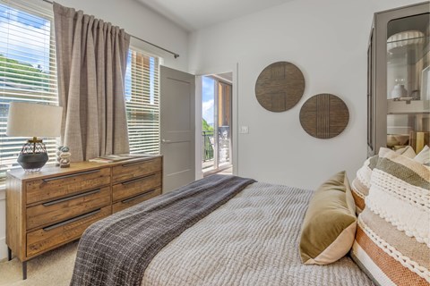 A bedroom with a bed, dresser, and window with curtains.