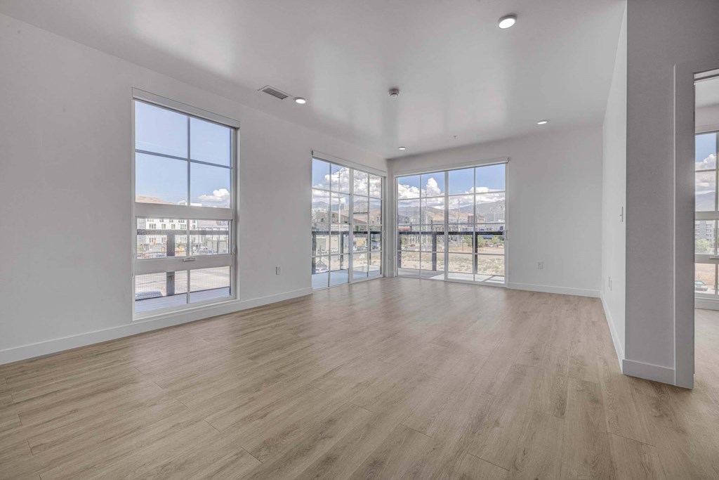 A spacious room with wooden floors and large windows overlooking a snowy landscape.