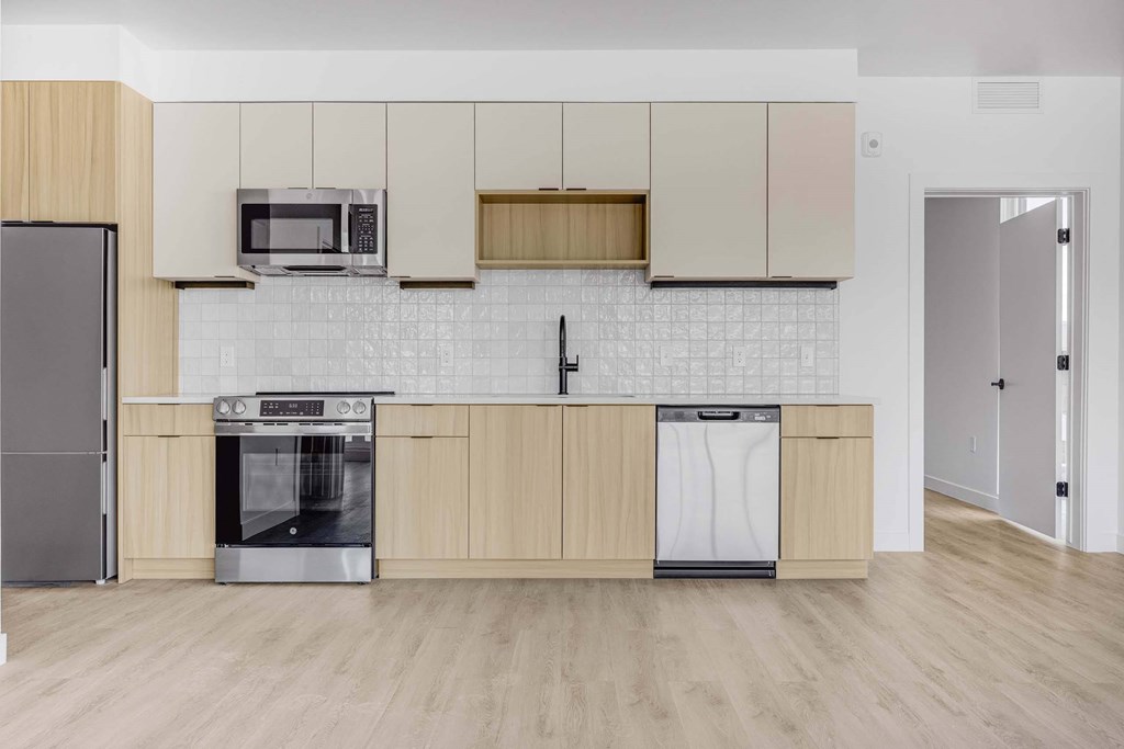 A kitchen with a refrigerator, microwave, oven, and dishwasher.