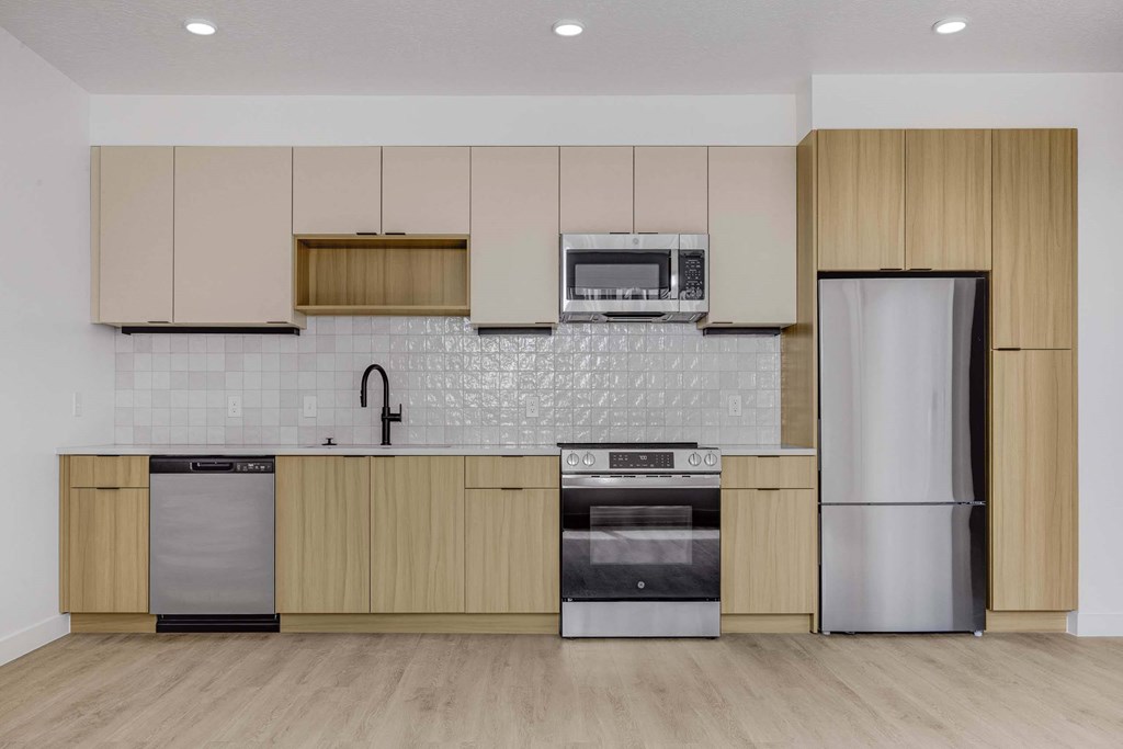 A kitchen with wooden cabinets and a white tiled backsplash.