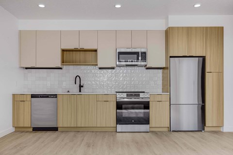 A kitchen with wooden cabinets and a white tiled backsplash.